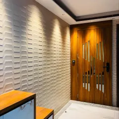A stylish entrance featuring a wooden door with diagonal slats for a modern, dynamic look. The adjacent wall is covered in 3D textured panels, all highlighted by warm spotlights for a dramatic effect.
