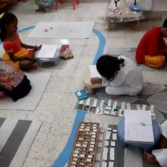 Here you can see the 'buzz' of a productive Montessori classroom. Children are engaged in various activities, some individually and some in small groups, all learning at their own pace in a calm, focused atmosphere.