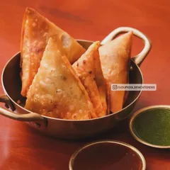Classic golden-fried samosas served in an elegant brass bowl. These crispy pastries are filled with a savory spiced potato and pea mixture, making them a timeless and beloved starter for any celebration.