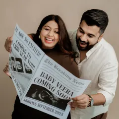 The pure joy of expecting parents. This photo beautifully captures the couple's excitement as they share their news with the custom-designed newspaper announcement I created for them.