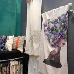 A display of our artisanal fabrics, including a stunning piece with a 3D embroidered portrait. This highlights the unique, art-like quality of our textiles, which can be used for everything from cushions to statement drapery.