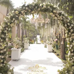 For this daytime wedding, we designed a heavenly aisle under a canopy of white floral arches and elegant chandeliers. It’s a testament to our love for creating serene, classic, and utterly romantic open-air ceremonies.