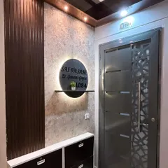 A welcoming and stylish entrance design. We combined a textured wall finish with dark wood fluted panels and a custom, back-lit nameplate to create a sophisticated entryway.
