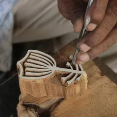 A close-up of a master carver's hands, meticulously shaping a floral motif. This image is from our collaboration with the Fabric Workshop Museum in Philadelphia, where we translate contemporary art into traditional woodblocks.