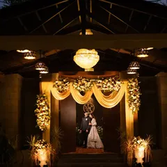 A grand, wide-angle shot of the couple at their engagement or reception, framed by the beautifully lit entrance of the venue. This captures the scale of the celebration.