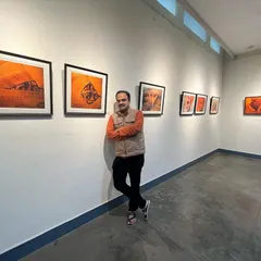 Standing with my work at a sand painting exhibition. It's a proud moment to see the pieces framed and displayed for people to experience.