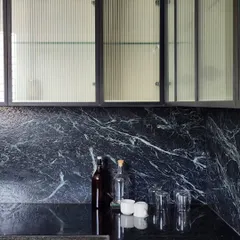 A detail from a contemporary kitchen, where we explored the interplay of textures. The combination of fluted glass, dramatic black marble, and warm wood creates a space that is both highly functional and visually sophisticated.