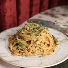 A rustic and comforting plate of Spaghetti Aglio e Olio. Garnished with fresh parsley, this dish is a testament to the beauty of simple ingredients prepared with care and expertise.