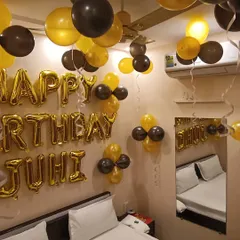 A classic and bold choice for a birthday celebration. This bedroom setup features a striking combination of black and gold balloons, with a personalized "Happy Birthday Juhi" message in large gold foil letters.