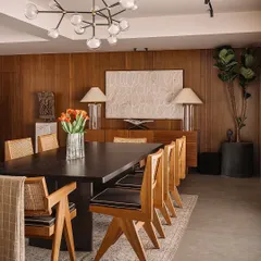 In this elegant dining room, a tall Fiddle Leaf Fig stands like a living sculpture. It adds vertical interest and a touch of natural softness that complements the warm wood tones and clean lines of the furniture.
