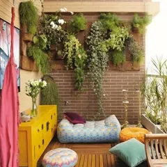 This eclectic balcony combines a lush vertical garden on a brick wall with colorful, bohemian floor seating. The mix of hanging plants, a bright yellow cabinet, and patterned poufs creates a vibrant and energetic vibe.
