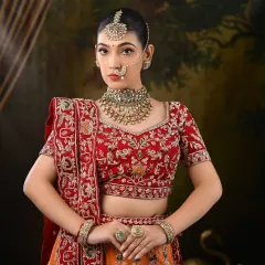 This bride is a vision in her red and orange embroidered lehenga. The makeup is kept classic and elegant to let the outfit and jewelry shine.