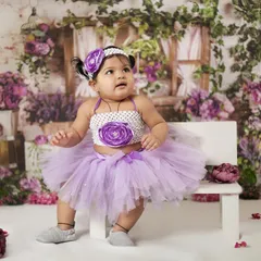 This 9-month-old baby girl is dressed in a purple tutu against a beautiful floral backdrop. This age is perfect for capturing their sitting milestone and expressive faces.