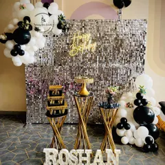For a chic and modern milestone birthday, we designed this stunning silver sequin shimmer wall. The black and white balloon garland, custom marquee letters, and elegant dessert stands create a glamorous photo-op for any adult celebration.