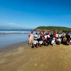 A large group photo on a pristine beach. The coastal trek is a great way to explore the hidden gems of Karnataka's shoreline.