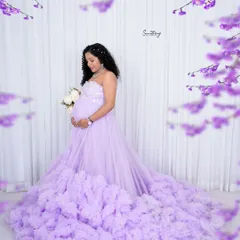 A dreamy solo portrait in a lavender ruffled gown. The floral accents and soft white background create a whimsical and ethereal look, perfect for a fairytale maternity shoot.