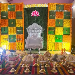 This is another view of a classic marigold flower backdrop, perfect for a baby shower or half saree function. The silver throne and the neatly arranged seer plates on the colorful mat create a festive and traditional look.