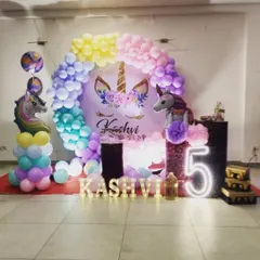 A dreamy unicorn-themed party with a pastel rainbow balloon arch. The decor includes a personalized backdrop, unicorn figures, and a light-up number "5" to add a touch of magic.