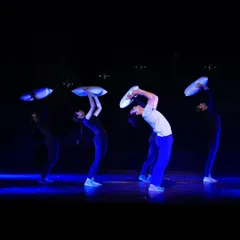 Four dancers perform a synchronized sequence in "ME & MY PILLOW." The stark blue lighting and the use of pillows as expressive props create a visually striking and emotionally charged atmosphere.