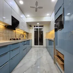 This is a parallel modular kitchen we designed for maximum efficiency and style. It features high-gloss acrylic finish cabinets in a calming powder blue and white, handleless drawers for a clean look, and integrated space for appliances, showcasing our ability to create functional yet beautiful kitchen layouts.