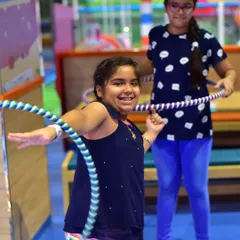 A girl smiles as she masters the hula hoop. My camps encourage kids to try new things and build confidence, with instructors on hand to guide and cheer them on.