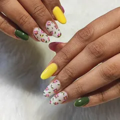 A fresh and vibrant look for spring. This set combines solid yellow and olive green nails with accent nails featuring a delicate, hand-painted pink floral pattern on a white base.