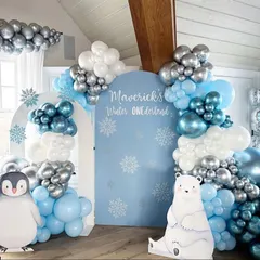 A magical 'Winter ONEderland' theme perfect for a first birthday. This cozy setup features penguin and polar bear cutouts and a beautiful balloon arch in shades of blue, white, and silver.