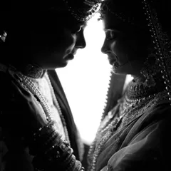 An intimate, high-contrast silhouette of the bride and groom. This artistic shot focuses on their connection, using light and shadow to create a classic wedding portrait.