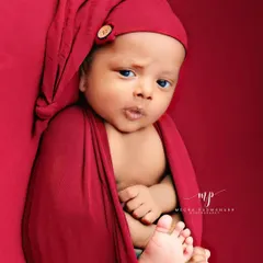 A curious and alert expression from this little one, wrapped in a red swaddle and matching hat.