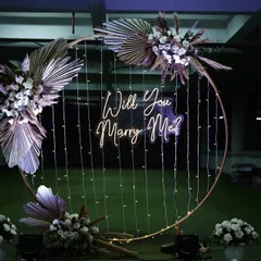 A full view of the modern circular proposal backdrop. This setup is perfect for open spaces, with its elegant gold frame, pampas grass arrangements, and glowing neon sign.
