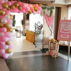 The entrance to Punarvi's party, designed to welcome guests into the fairytale. A pink, white, and gold balloon arch frames the doorway, complemented by a personalized welcome sign on an easel, setting the tone from the moment guests arrive.