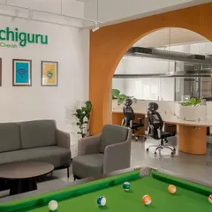 The breakout space at the Hosachiguru office, complete with a pool table and comfortable lounge seating. An archway finished in textured terracotta paint connects this recreational area to the main workspace.