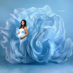 This is what a dream looks like. We used yards of flowing blue fabric to create a cloud-like effect, making the mom-to-be look like she is floating in a serene sky.