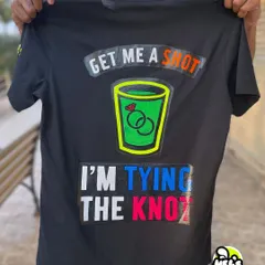 The back of our custom bachelor party T-shirt. It features a neon green shot glass and the text "Get me a shot, I'm tying the knot," all painted with glow-in-the-dark colors.