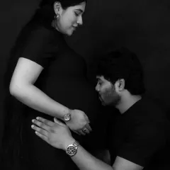 A tender moment captured in classic black and white. The father-to-be kissing the baby bump is a timeless expression of love, made even more powerful in monochrome.