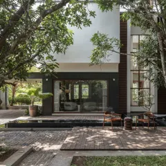 For the Mango Tree Yard residence in Kerala, we designed the home around two mature mango trees. This view from the backyard highlights the seamless blend of indoor and outdoor spaces, with a tranquil waterbody and deck creating a serene living experience connected to nature.