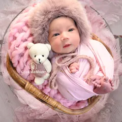 Here is the same baby girl, now awake and curious, wearing an adorable furry hood and posing with her teddy bear companion.