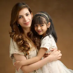 A classic mother-daughter embrace against a warm, brown painterly backdrop. The soft lighting and their close hug create a timeless and elegant portrait that feels intimate and heartfelt.