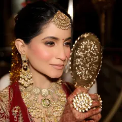 A beautiful candid moment of the bride admiring her final look. I focused on a soft, rosy blush and a neutral lip to balance the heavy jewelry, creating a look of timeless elegance for her wedding day.