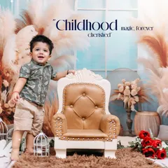A toddler stands proudly next to a miniature throne in our studio. This first birthday setup features a boho theme with pampas grass, creating a trendy and celebratory portrait.