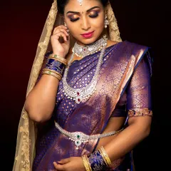 A stunning studio shot of a South Indian bridal look. The rich purple Kanjivaram saree is complemented by diamond jewellery and a dramatic purple smokey eye, showing how we can blend tradition with modern makeup trends.