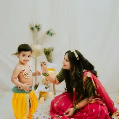 A mother lovingly applies a 'teeka' to her little Krishna. This is a sweet, traditional moment captured during our special festive photoshoot.