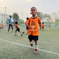 The pure joy of football. A young player from our grassroots program runs on the pitch with a huge smile, embodying the fun-first environment we create.