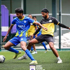 Two players from Dell and another corporate team locked in a competitive duel during a Just Fives League match. The intensity and focus show how seriously teams take the competition.