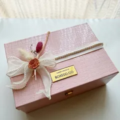 This pink leather-finish box is a sophisticated choice for a wedding invitation hamper. The exterior is adorned with a delicate ribbon and wax seal, hinting at the curated gifts waiting inside.