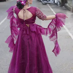 The back view of this stunning wine-colored organza lehenga, featuring a keyhole back and dramatic ruffled sleeves for a modern, high-fashion statement.