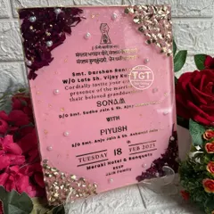 An angled view of the pink resin invitation, showing its thickness and the glossy, smooth surface.