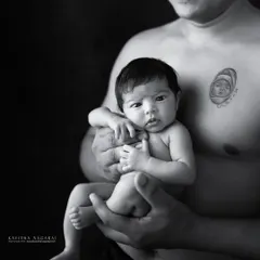A father's arms, a baby's safe haven. This powerful black and white portrait captures the strength and tenderness of a new dad holding his nine-day-old daughter.