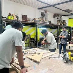 Learning happens together here. This shot captures a typical weekend workshop where our instructor guides a group of new makers through the fundamentals of woodworking, ensuring everyone is comfortable and safe before they start their own projects.