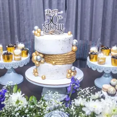 A stylish white, gold, and silver themed dessert table for Nikhil's 50th birthday bash. The two-tier cake is complemented by custom dessert shots.